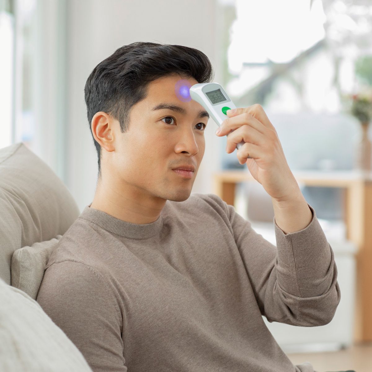 Man measuring his forehead temperature with a Medisana infrared thermometer.